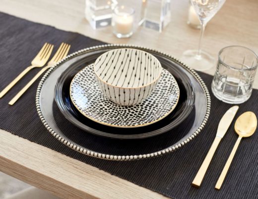 table with black tablecloth, plate, gold flatware, and patterned bowls