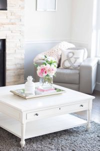 White coffee table with a vase of pink flowers on top