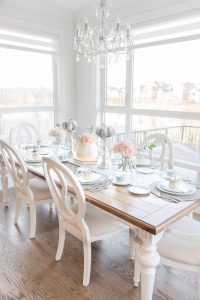 Dining table with place settings, candles and flowers on top